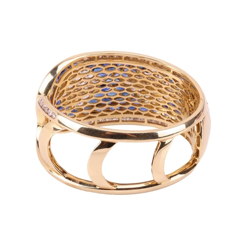 79 - A sapphire and diamond-hinged bangle the tapered plaque decorated throughout with oval-cut sapphires... 