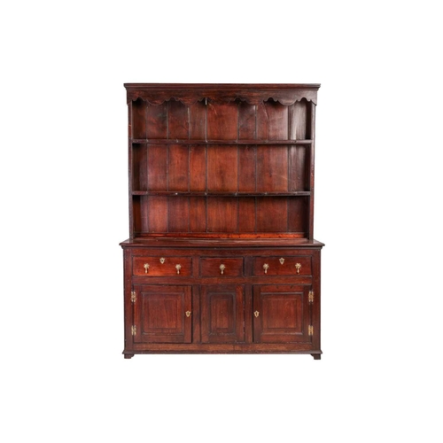 116 - A George III provincial Oak cupboard-based dresser and rack, the rack with a decorative shaped corni... 