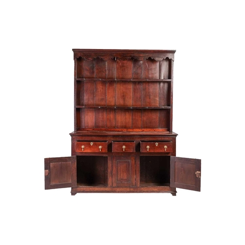 116 - A George III provincial Oak cupboard-based dresser and rack, the rack with a decorative shaped corni... 