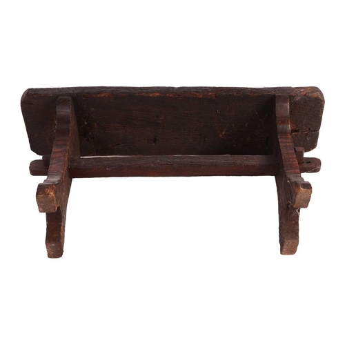 117 - A primitive vernacular oak/elm form stool, 19th century, with thick knarled rectangular top over a b... 