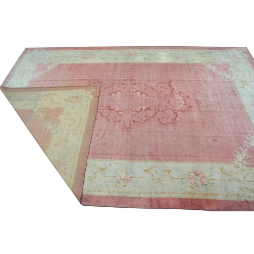 142 - A muted red/pink ground Austrian Savonerie style, neo-classical carpet, C1900, with a large subtle c... 