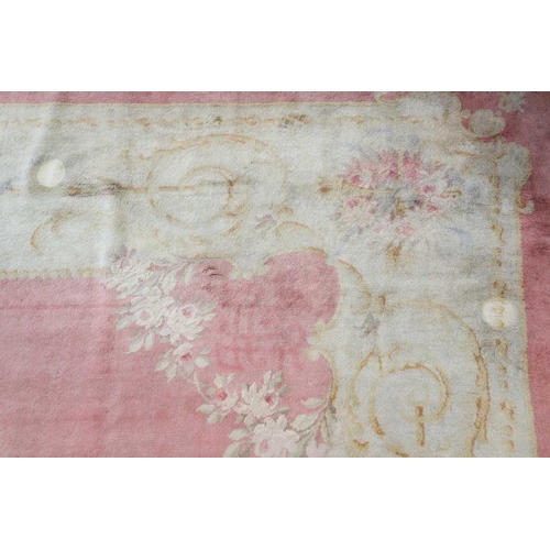 142 - A muted red/pink ground Austrian Savonerie style, neo-classical carpet, C1900, with a large subtle c... 