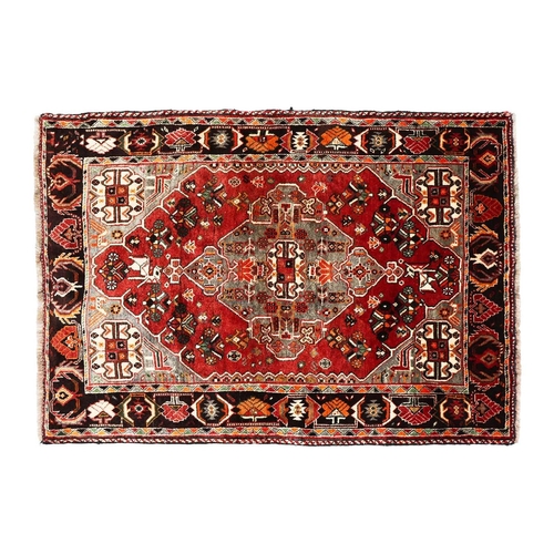 144 - A plum-coloured ground Baktiari rug with a central diamond lozenge, within a dark indigo geometric b... 