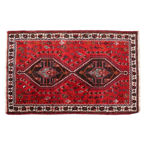 145 - A red ground Qashqai rug with two diamond lozenges on a central pole within multiple borders.170 cm ... 