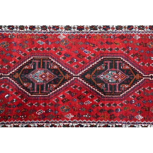 145 - A red ground Qashqai rug with two diamond lozenges on a central pole within multiple borders.170 cm ... 