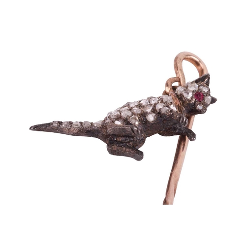 15 - An Edwardian gem-set cat stick pin, the shepherd's crook pin stem dangling a sculpted cat being pick... 