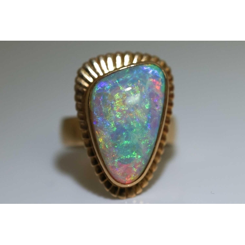 3 - A large opal cocktail ring, the gadrooned triangular head collet-set with a free-formed polished pre... 