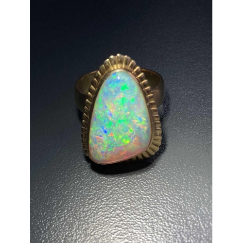 3 - A large opal cocktail ring, the gadrooned triangular head collet-set with a free-formed polished pre... 