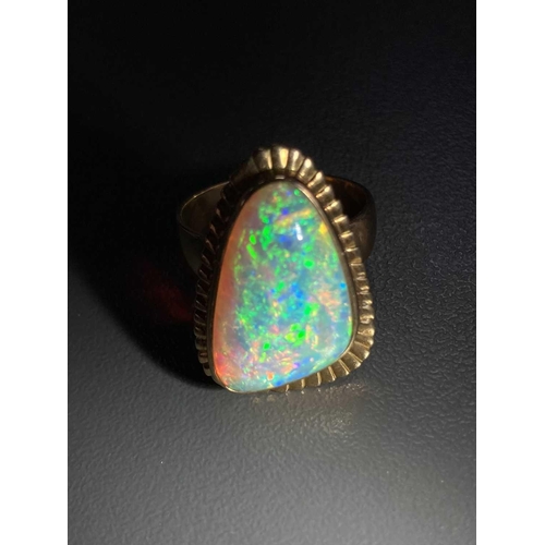 3 - A large opal cocktail ring, the gadrooned triangular head collet-set with a free-formed polished pre... 