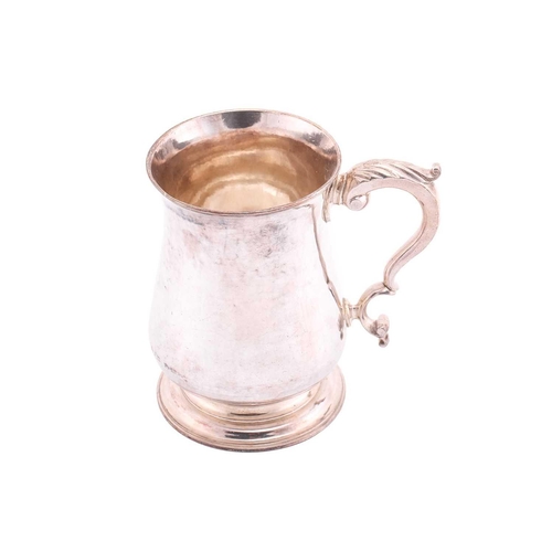 329 - A George III silver tankard; plain low-bellied form, on circular stepped base; with leaf-capped scro... 