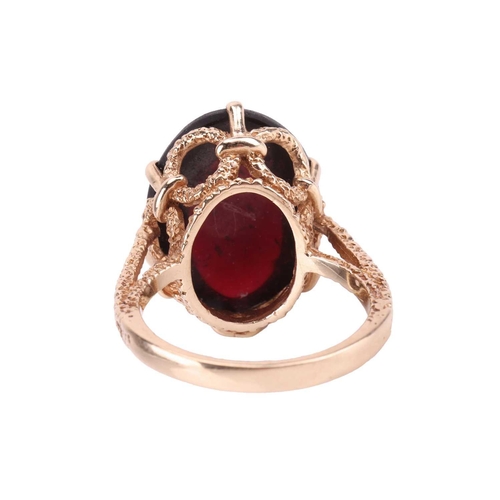 5 - A garnet 'carbuncle' dress ring in 9ct gold, claw-set with an oval garnet cabochon of 20.0 x 15.2 x ... 