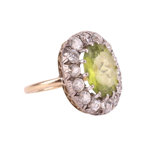 65 - An Edwardian peridot and diamond entourage ring, centred with an oval-cut peridot of bright yellowis... 