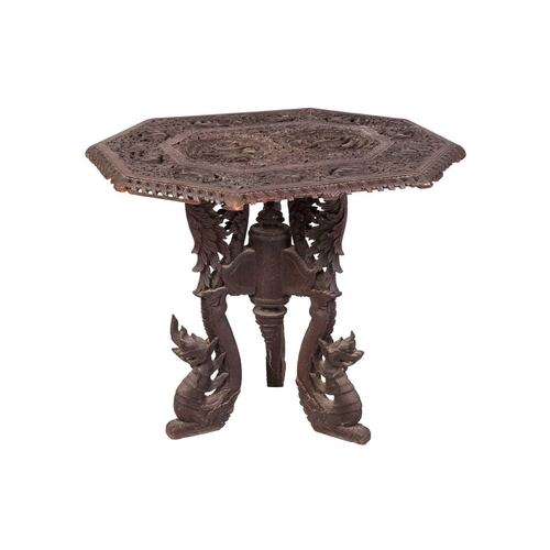 113 - An Indian carved hardwood octagonal table, the top relief carved with elephants and peacocks, on thr... 