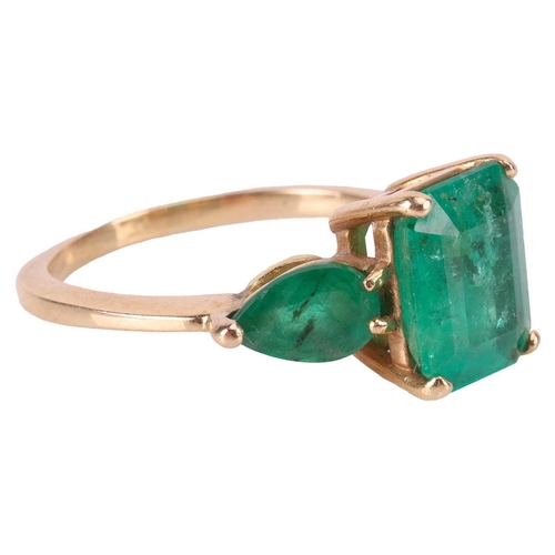 14 - An emerald trilogy ring, centred with a step-cut emerald with canted corners of 9.8 x 8.1 x 5.2 mm, ... 