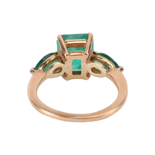 14 - An emerald trilogy ring, centred with a step-cut emerald with canted corners of 9.8 x 8.1 x 5.2 mm, ... 