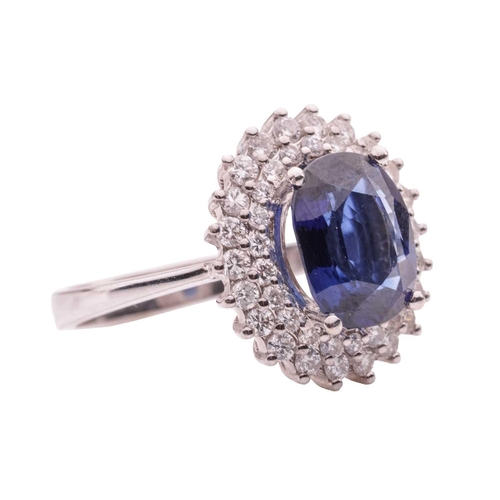 36 - A synthetic sapphire and diamond cluster ring, comprising a central claw-set oval-cut synthetic sapp... 