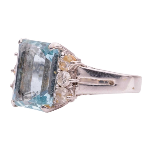 67 - An aquamarine and diamond dress ring, featuring a rectangular step-cut aquamarine with canted corner... 