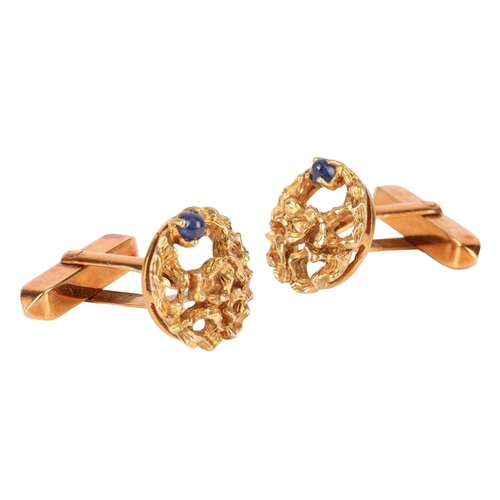 117 - A pair of cufflinks, of organic openwork design, each claw-set with a cabochon blue sapphire, the cu... 
