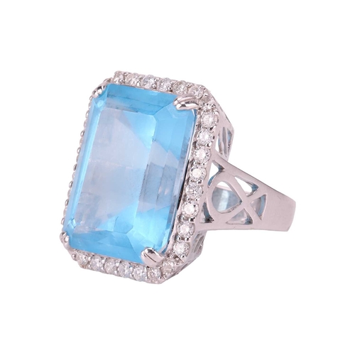 84 - A large topaz and diamond halo ring, featuring a large rectangular step-cut Swiss blue topaz with ca... 