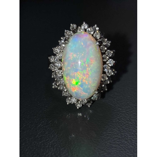 90 - An opal and diamond cluster ring, centred with an oval cabochon precious opal, displaying vibrant sp... 