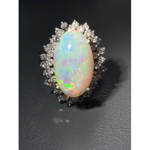 90 - An opal and diamond cluster ring, centred with an oval cabochon precious opal, displaying vibrant sp... 