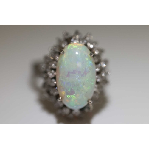90 - An opal and diamond cluster ring, centred with an oval cabochon precious opal, displaying vibrant sp... 