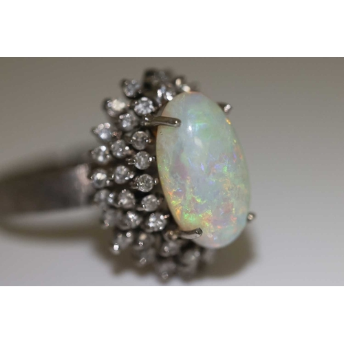 90 - An opal and diamond cluster ring, centred with an oval cabochon precious opal, displaying vibrant sp... 