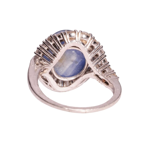 94 - A star sapphire and diamond cluster ring, comprising a claw-set high domed sapphire cabochon of medi... 