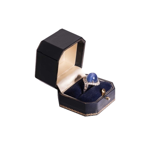 94 - A star sapphire and diamond cluster ring, comprising a claw-set high domed sapphire cabochon of medi... 