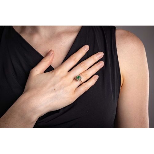 19 - An emerald and diamond cluster ring, comprising a central emerald-cut emerald collet-set in yellow m... 