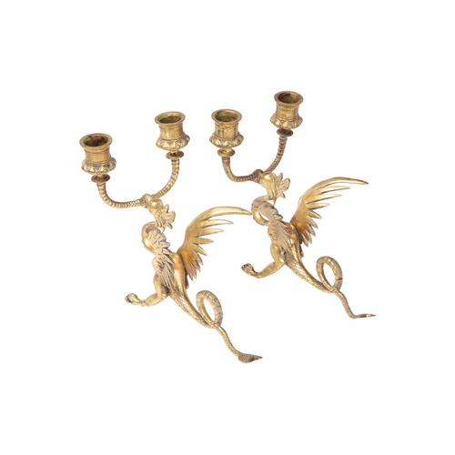 190 - A pair of Gothic-style brass two-branch candlesticks, modelled as gryphons, 21 cm high x 21 cm, toge... 