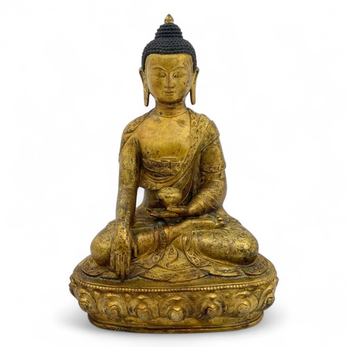 252 - A mid-20thC Nepalese gilt-patinated and aged hollow cast bronze Buddha in bhumisparsha mudra on a lo... 