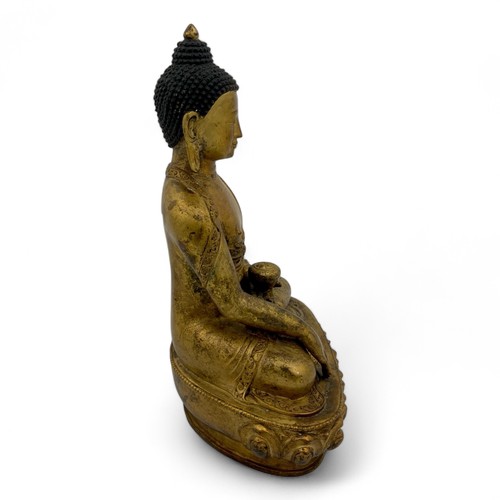 252 - A mid-20thC Nepalese gilt-patinated and aged hollow cast bronze Buddha in bhumisparsha mudra on a lo... 