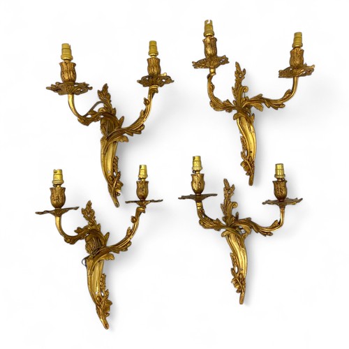 224 - A set of four mid-late 20thC Louis XV style gilt metal Rococo style wall sconces, with leaf and acor... 