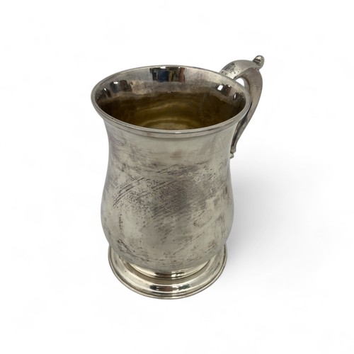 121 - A George II silver tankard, of plain finish with a scroll handle, the body with an erased inscriptio... 