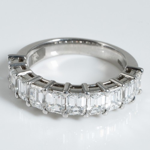 150 - A George Pragnell Ltd platinum and diamond half hoop or half eternity ring, claw set with 10 emerald...