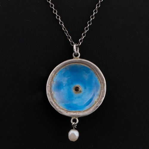 85 - An Arts and Crafts enamel pendant, c.1905, decorated with blue enamel set within a contoured wirewor... 