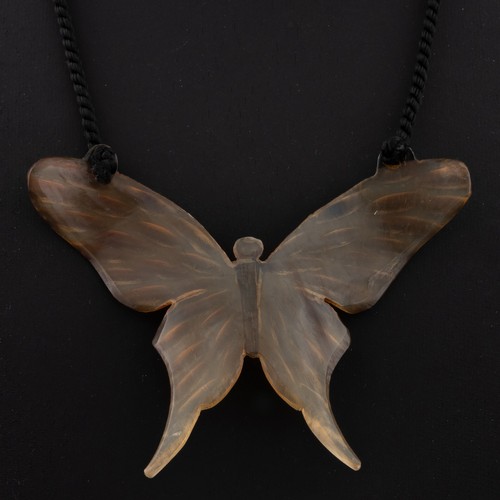 135 - An Art Nouveau horn pendant, translucent carved horn with flecks of amber and gold colour on the win... 