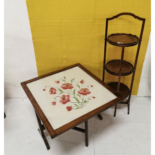 146 - Vintage era oak framed fire screen, folding to a low table, labelled  Logan, inset with a red flor... 