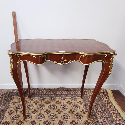 181 - Serpentine shaped French Occasional Table, with a parquetry style top, brass banding and gilt mounts... 