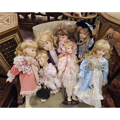 573 - 8 porcelain Dolls, wearing blue, pink etc costumes