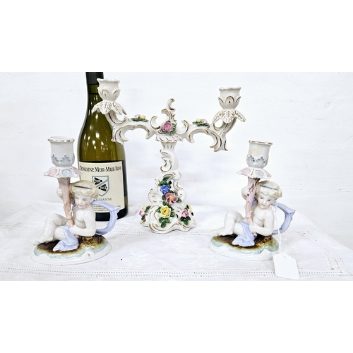 372 - Pair of German porcelain low sized candlesticks with cherubs and an ornate two-branch floral candela... 