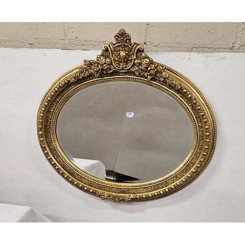 144 - Decoratively Carved Wall Mirror, gilt oval shaped, with floral pediment carvings, 92cmH x 99cmW