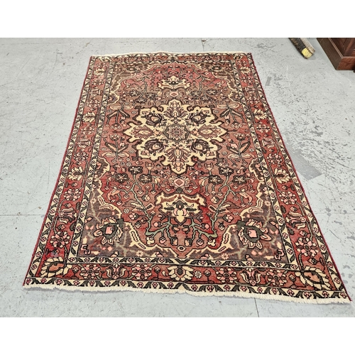 251 - Washed red ground vintage Persian Heriz Rug, hand woven with a floral pattern, 1.95m x 1.35m