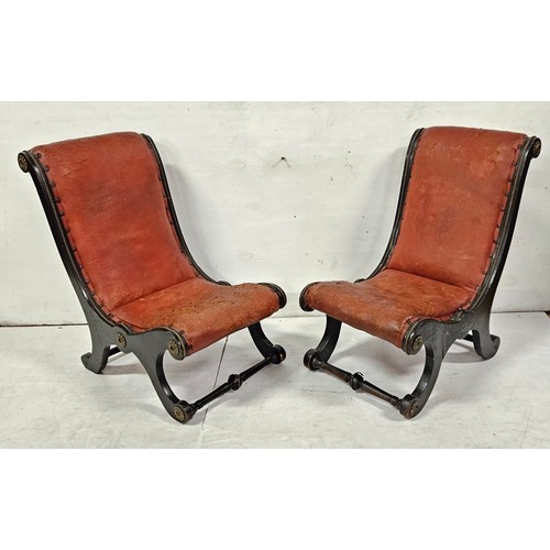 57 - Matching Pair of Regency ebonised low-seat Slipper Chairs, with worn crimson hide seats, brass trims... 
