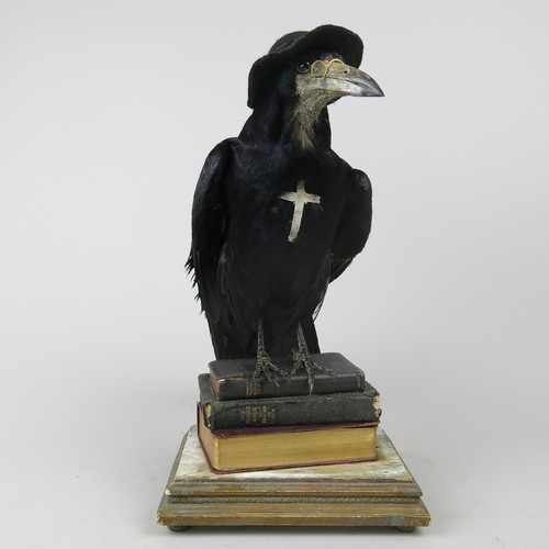 32 - ANTHROPOMORPHIC TAXIDERMY ROOK, dressed as a parson with hat and spectacles, mounted on bibles. 
Ex ... 