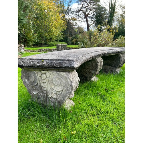 68 - A reconstituted stone curved garden bench on five scroll supports, each marked 