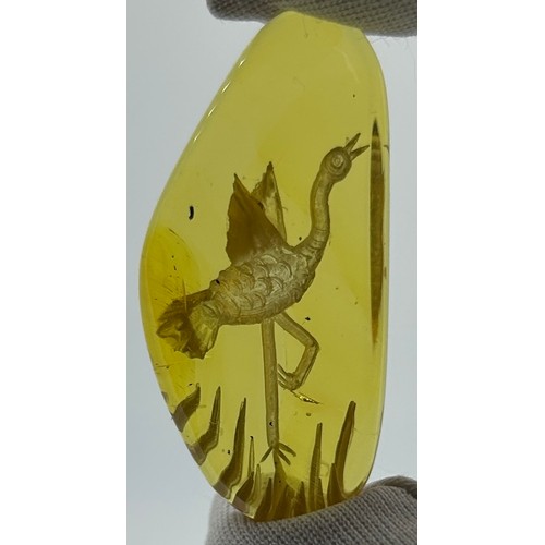 38 - A SET OF THREE AMBER SPECIMENS, carved from reverse with floral motifs, hummingbirds and cranes.