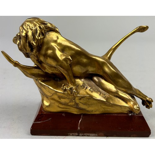 181 - A SCULPTURAL GILT BRONZE OF A LION, mounted on a red marble base and signed indistinctly.

16cm in l... 