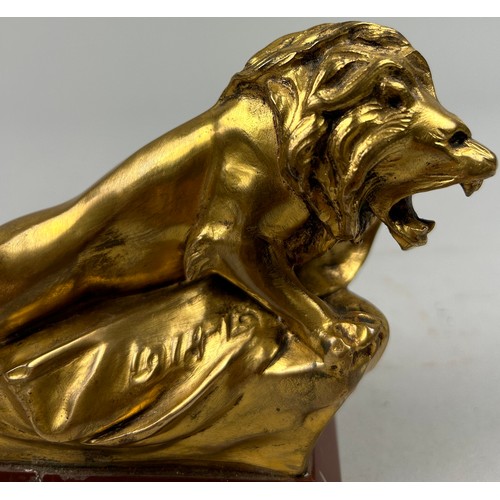 181 - A SCULPTURAL GILT BRONZE OF A LION, mounted on a red marble base and signed indistinctly.

16cm in l... 